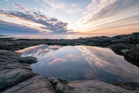 Dramatic sky reflection in tide pool at dawn ocean shore
