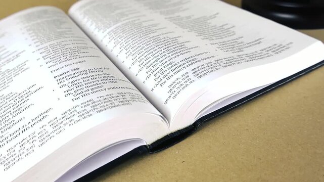 Open Holy Bible with a judge's wooden gavel resting beside it, symbolizing the intersection of divine law, morality, spiritual guidance, and the justice system on a simple brown background