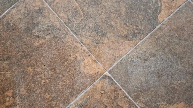 Close-up of ceramic or porcelain floor tiles with a brown stone texture. Home renovation materials, interior design background, architectural building finish.