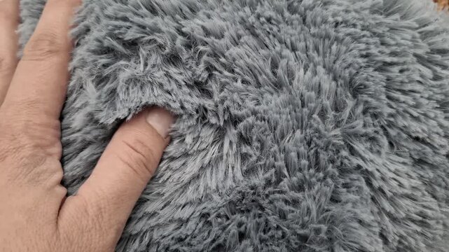 Woman hand touching a soft blue fluffy faux fur texture. Soft fabric material, cozy home decor, tactile sensory experience