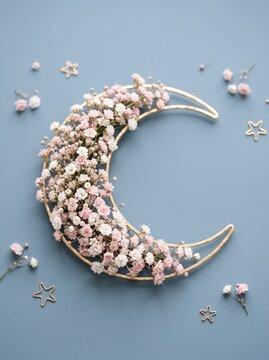 Decorative golden crescent moon wreath adorned with delicate pink and white babys breath flowers