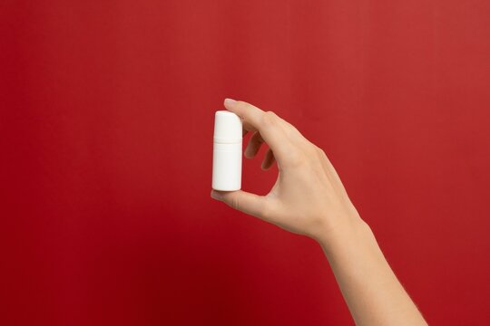 Hand holding blank white cosmetic roll-on bottle