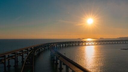 Fototapeta premium Panoramic view of an aerial suspension highway curving over the ocean at dusk
