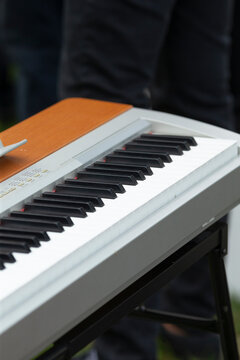 Closeup white keys of electric keyboard showing keybed and matte texture, soft ambient light and partial stand hint at live performance or rehearsal