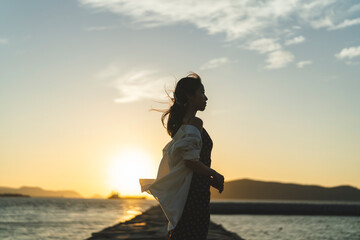 Fototapeta premium 夕暮れの海にいる女性