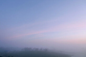 Obraz premium Soft Pastel Sunrise Sky Over Foggy Countryside Village