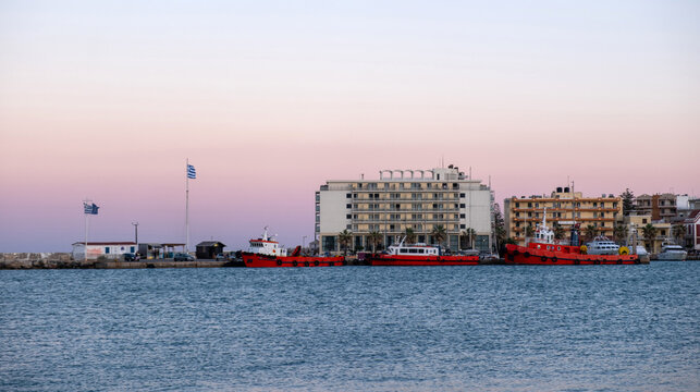 Red tugboats moored at the harbor quay, waterfront town buildings, Chios Island, Greece