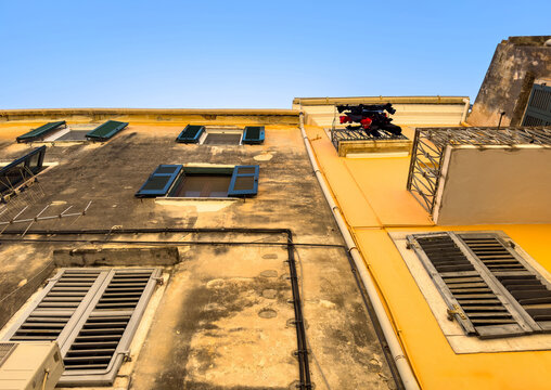 Weathered plaster facades with wooden shutters and laundry, upward view in Corfu Old Town, Greece