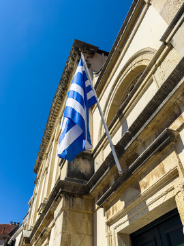 Greek flag on weathered stone facade with arched windows, Corfu Old Town, Greece