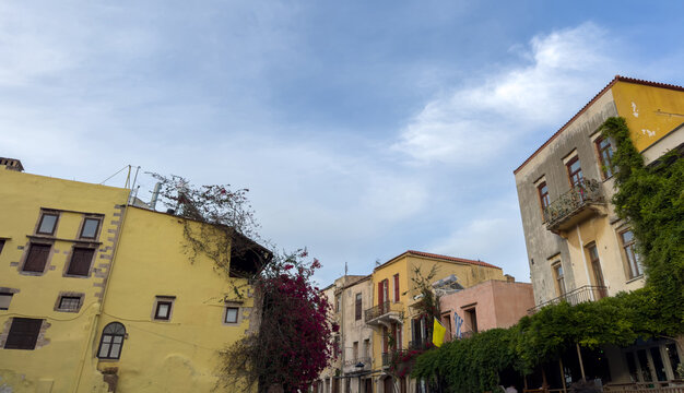 Weathered pastel facades with balconies and bougainvillea on spring street in Chania, Greece