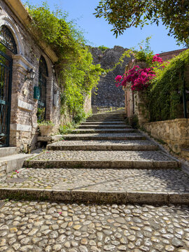 Cobblestone steps with stone houses and pink bougainvillea, Corfu Old Town, Greece