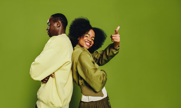 Back-to-back friends pose in a studio portrait with playful movement and confidence