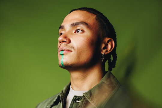 Thoughtful man portrait with artistic face paint in a modern studio scene