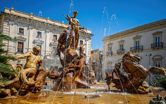 Majestic Fontana di Diana with spraying water jets against beautiful historic palaces. Premium Sicilian travel stock photography from the heart of Ortigia Island.