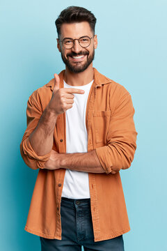 A portrait of a smiling man with glasses, a beard, and a multicolored shirt over a white shirt, set against a solid vivid background.