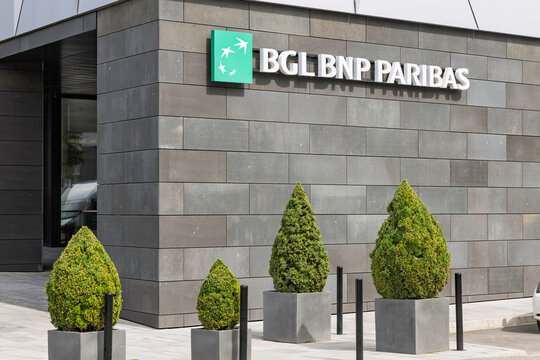 Luxembourg City, Luxembourg - 7 August 2026: Main entrance of BGL BNP Paribas corporate building featuring green topiary trees and stone facade.
