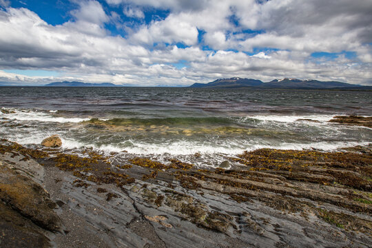 Rugged rocky coastline with crashing waves and cloudy dramatic sky over the atlantic ocean, landscape Patagonia.