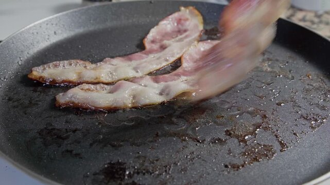 Lonchas de bacon en una sart&eacute;n cocinandose a fuego lento