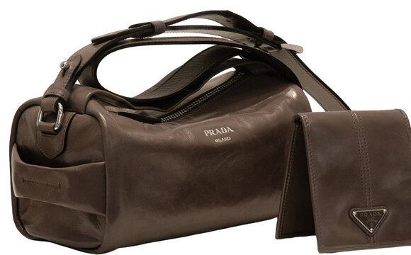 A vintage-style Prada shoulder bag, crafted from soft dark brown leather with an aged finish, accompanied by a matching wallet featuring a triangular enamelled logo. Milan &ndash; Italy, 24 August 2026