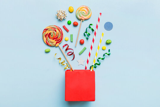 gift box in corner full of assorted traditional candies falling out on colored background with copy space. Happy Holidays sale concept