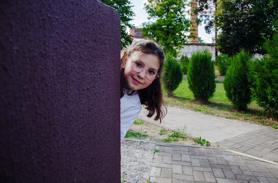 Student looks around a corner of the school as she gets ready for the school year. She smiles and appears curious