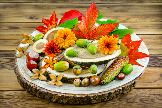 Nat&uuml;rliche Dekoration im Herbst mit Kastanien, Eicheln, Blumen und Herbstlaub auf Holz