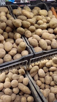 Grocery store shelves filled with fresh vegetables, including potatoes, carrots, and onions. The video shows the produce department of a supermarket with raw vegetables arranged for retail sale.