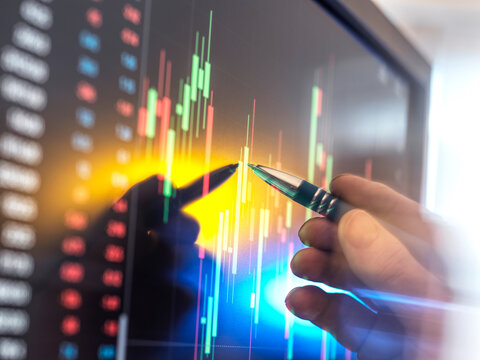 Male stock trader points at financial data on a computer screen