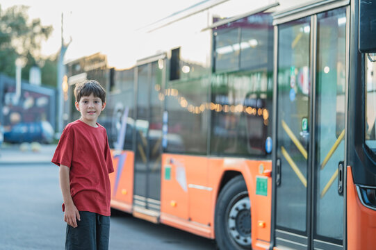 Boy wearing a red shirt waits for the city bus