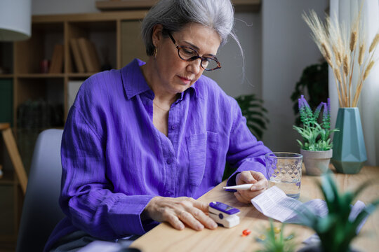 Woman using glucose monitor for diabetes self test at home