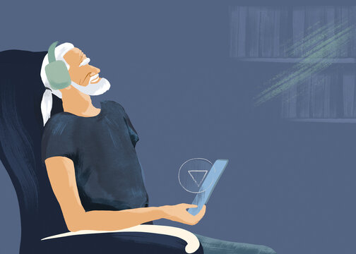 Senior man listens to an audiobook using a tablet and headset