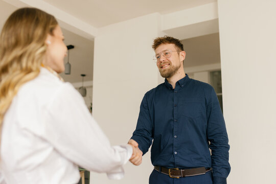 A businessman and a businesswoman shake hands during a job interview