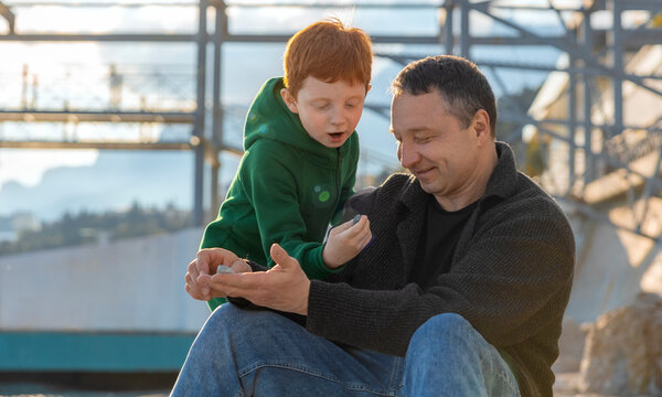 Father and son examine a rock on the beach
