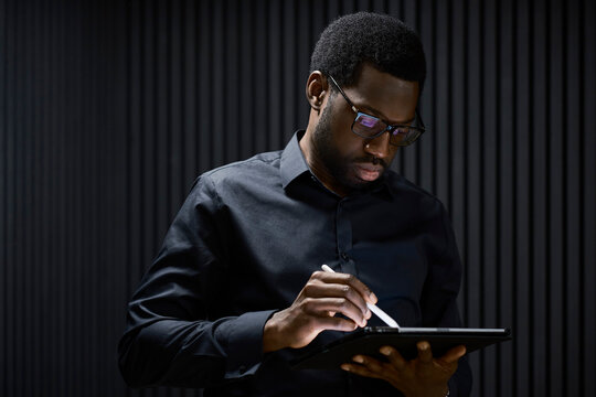A professional man works on a tablet computer in a dark office