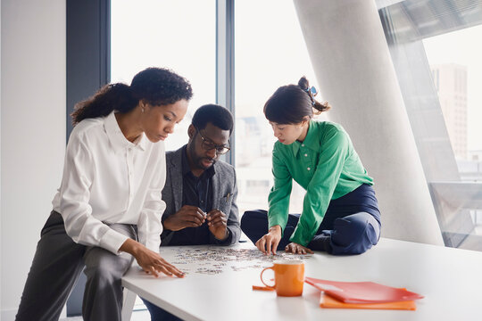 A business team solves a jigsaw puzzle on a boardroom table