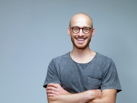 Portrait of smiling man with crossed arms in front of grey background