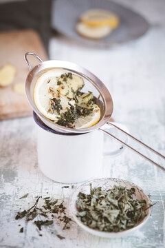 Brewing peppermint ginger tea with lemon in a metal strainer