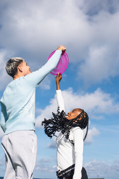 Young man and mid adult woman playing with frisbee outdoors