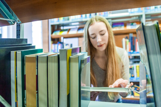 Teenage girl behind bookshelf in a public library