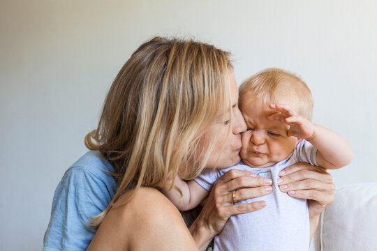Mother kissing her grimacing baby girl