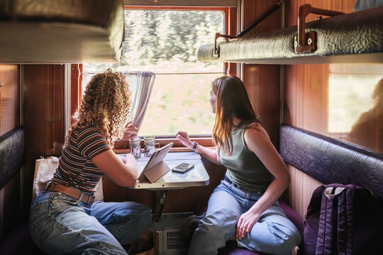 Friends watch the scenic landscape from a train compartment