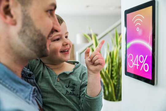 Father and son use a smart home control panel indoors