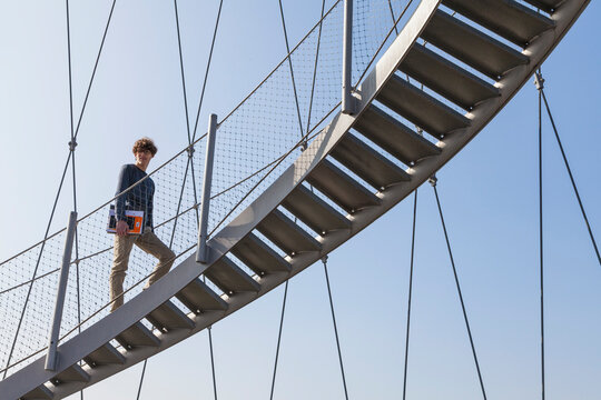 Student walks up metal staircase outdoors holding a folder