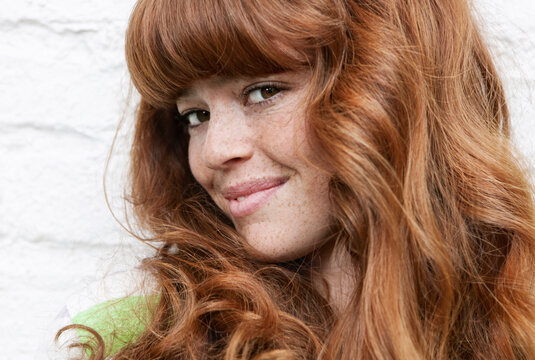 Smiling woman with red hair looks at camera in Berlin