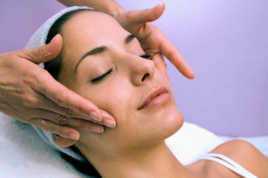Young woman receiving facial massage, eyes closed, close-up