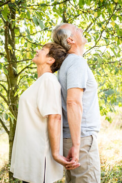 Happy senior couple stading back to back outdoors
