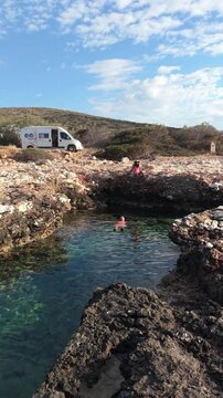 Explore the serene beauty of Paros Island, where visitors enjoy swimming in clear waters surrounded by stunning rocky landscapes. A couple relaxes by the ocean natural pool