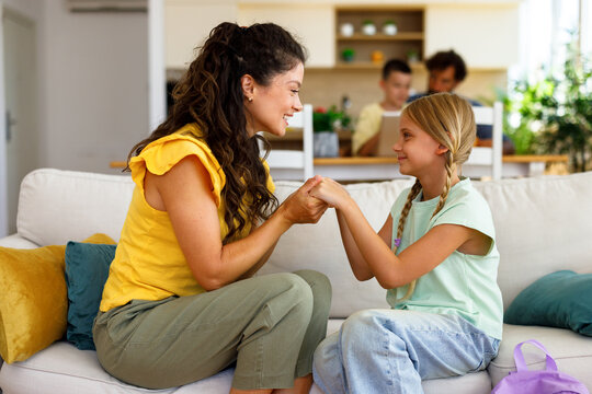 Mother helping her daughter get ready for school by adjusting her backpack at home