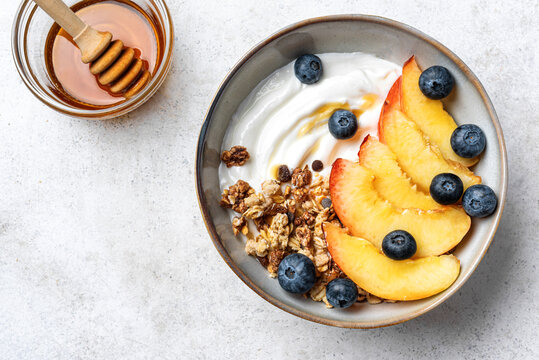 Granola bowl with yogurt, peach, blueberries and honey