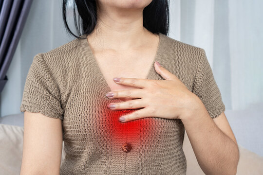 Asian woman touching her chest suffering from heartburn, acid reflux, GERD, and chest pain with red highlighted area. Ideal for medical, healthcare, and digestion concept